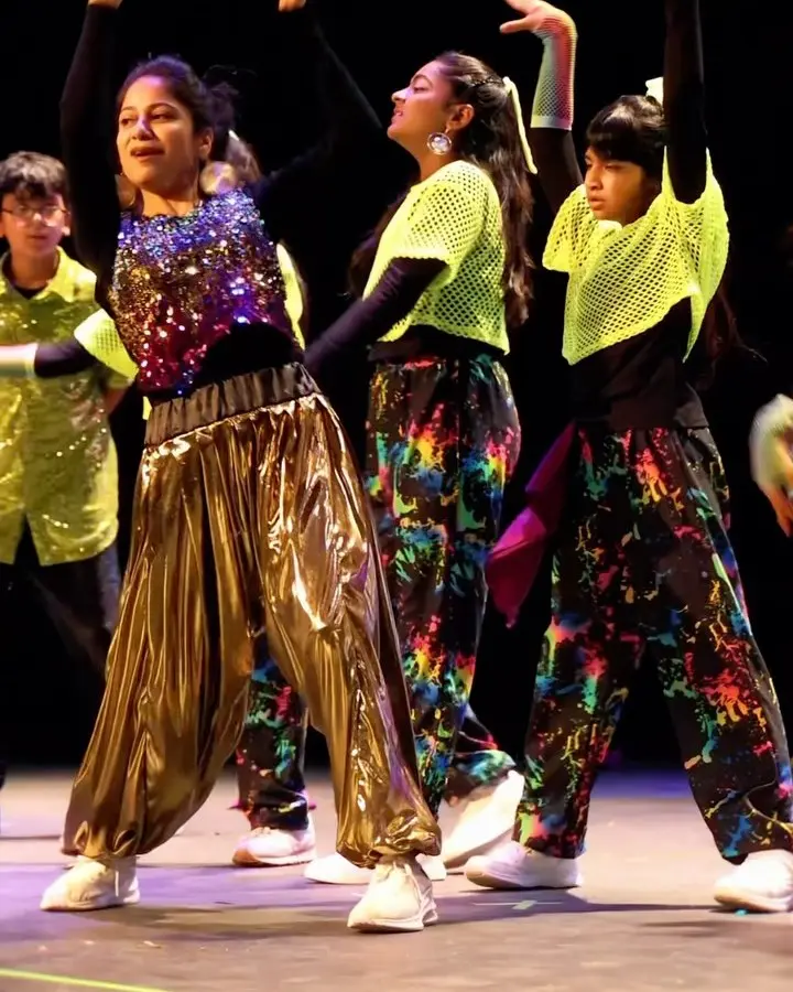 Dancers in gold and neon costumes performing at AMMA Atlanta Onam