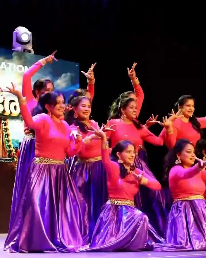 Dance troupe in pink and purple on stage at AMMA Onam 2026