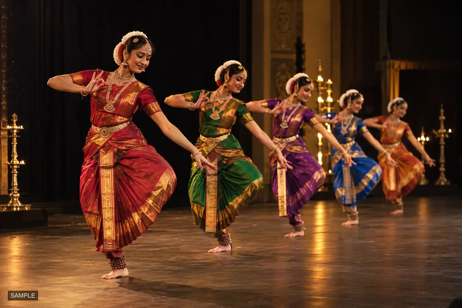 Classical dancers in silk costumes performing in a line on stage